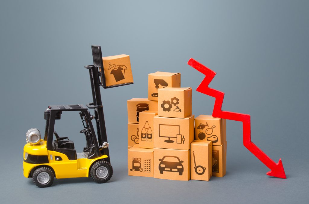 Forklift with boxes and red arrow down. Drop of performance production of goods. Import export trading, economic recession. Low demand and overstock. Overproduction. Slowdown in economic development.