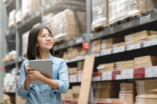 Young attractive Asian worker, owner, entrepreneur woman holding smart tablet
